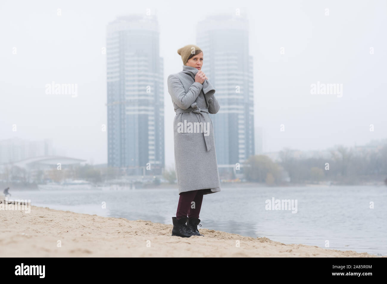 Giovane donna a piedi da solo indossando un cappotto grigio Foto Stock