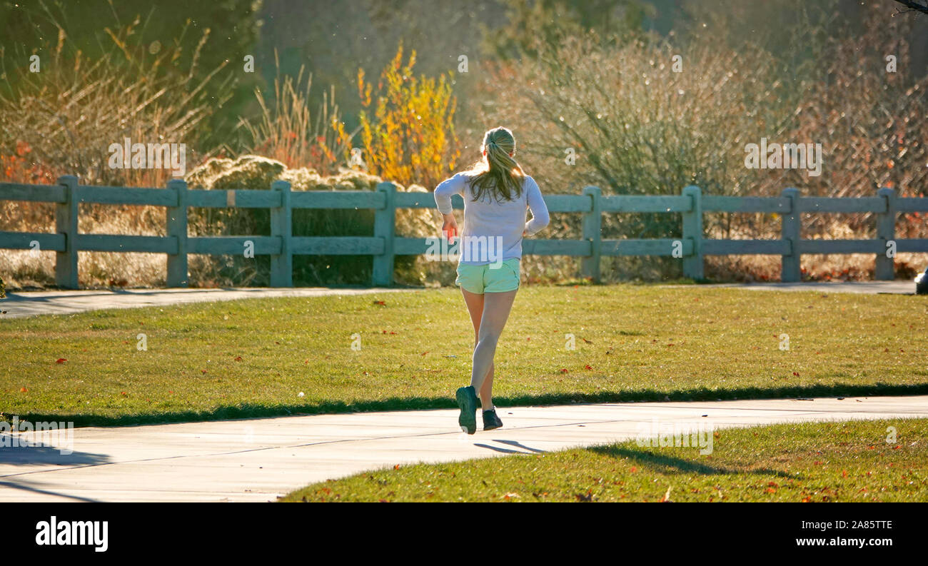 Una donna in esecuzione o fare jogging lungo un fiume di percorso nel vecchio mulino sezione di piega, Oregon Foto Stock