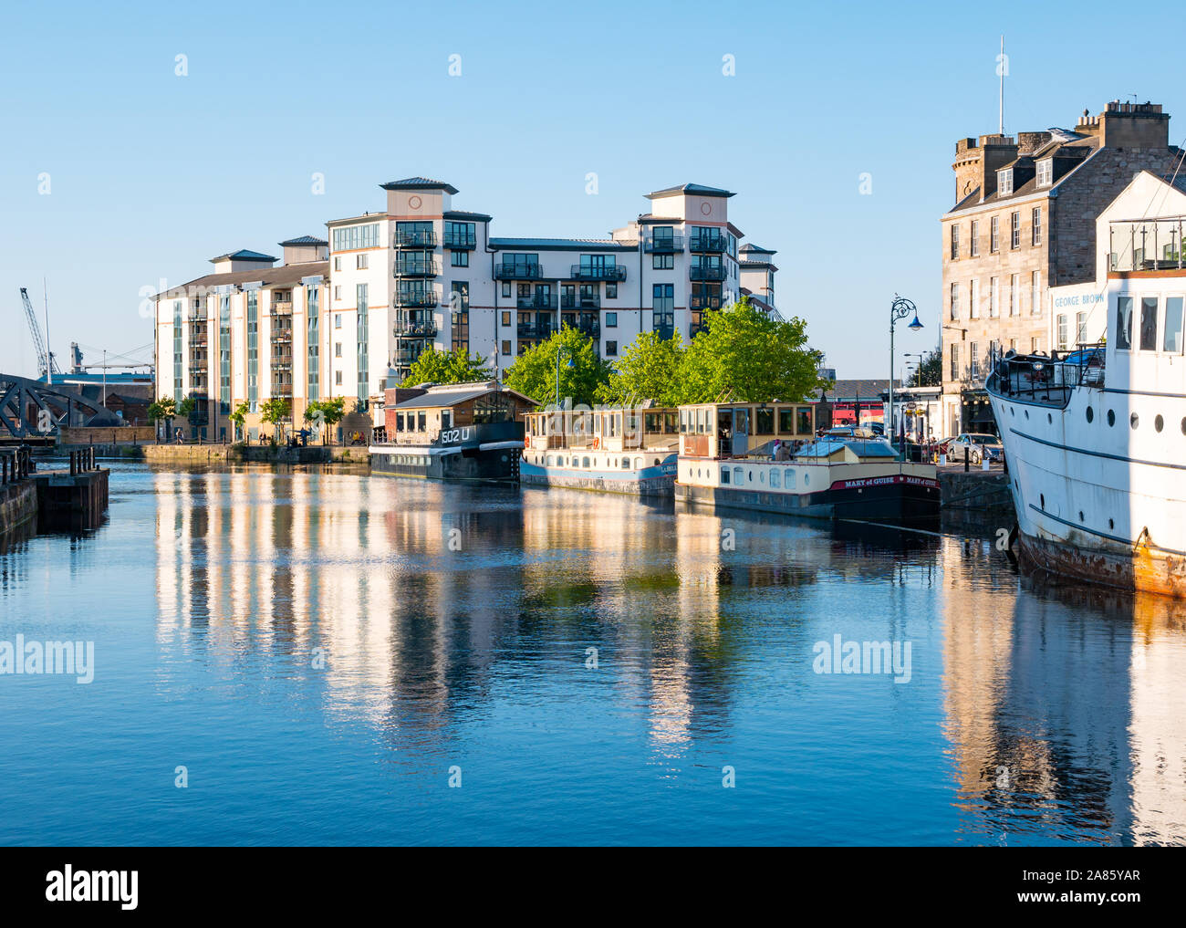 Blocco di appartamenti a barca e riflessioni, acqua di Leith fiume al tramonto, la Riva, Leith, Edimburgo, Scozia, Regno Unito Foto Stock
