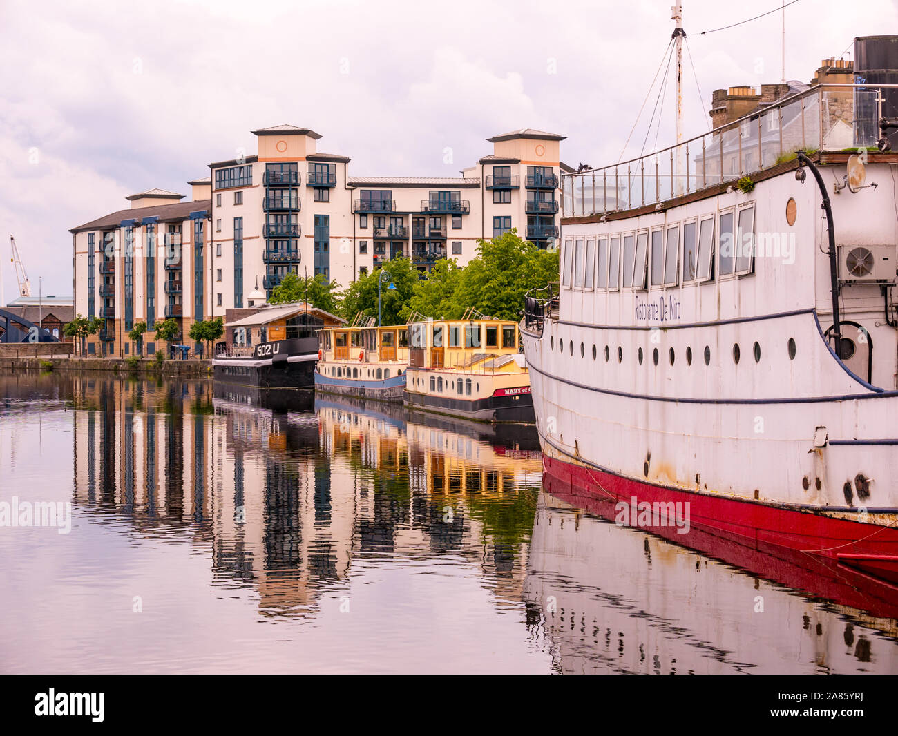 Blocco di appartamenti a barca e riflessioni, acqua di fiume di Leith al tramonto la riva, Leith, Edimburgo, Scozia, Regno Unito Foto Stock
