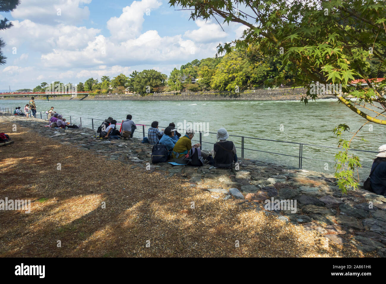 Uji, Giappone - le persone anziane seduto accanto al fiume su una soleggiata giornata autunnale Foto Stock