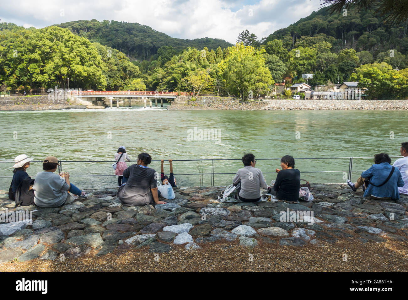 Uji, Giappone - le persone anziane seduto accanto al fiume su una soleggiata giornata autunnale Foto Stock