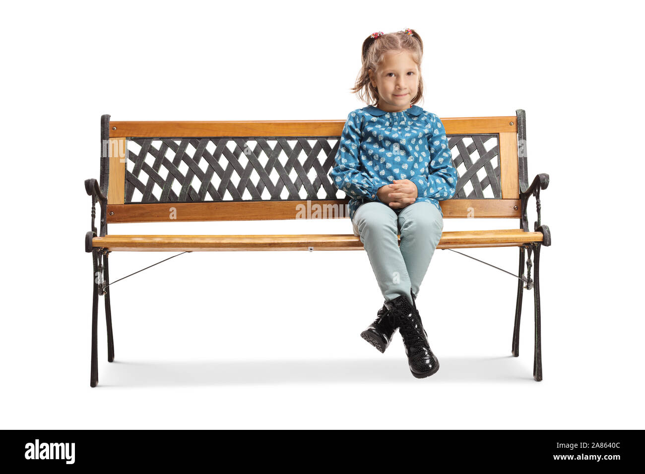 A piena lunghezza Ritratto di una bambina seduta su una panchina e guardando la telecamera isolata su sfondo bianco Foto Stock
