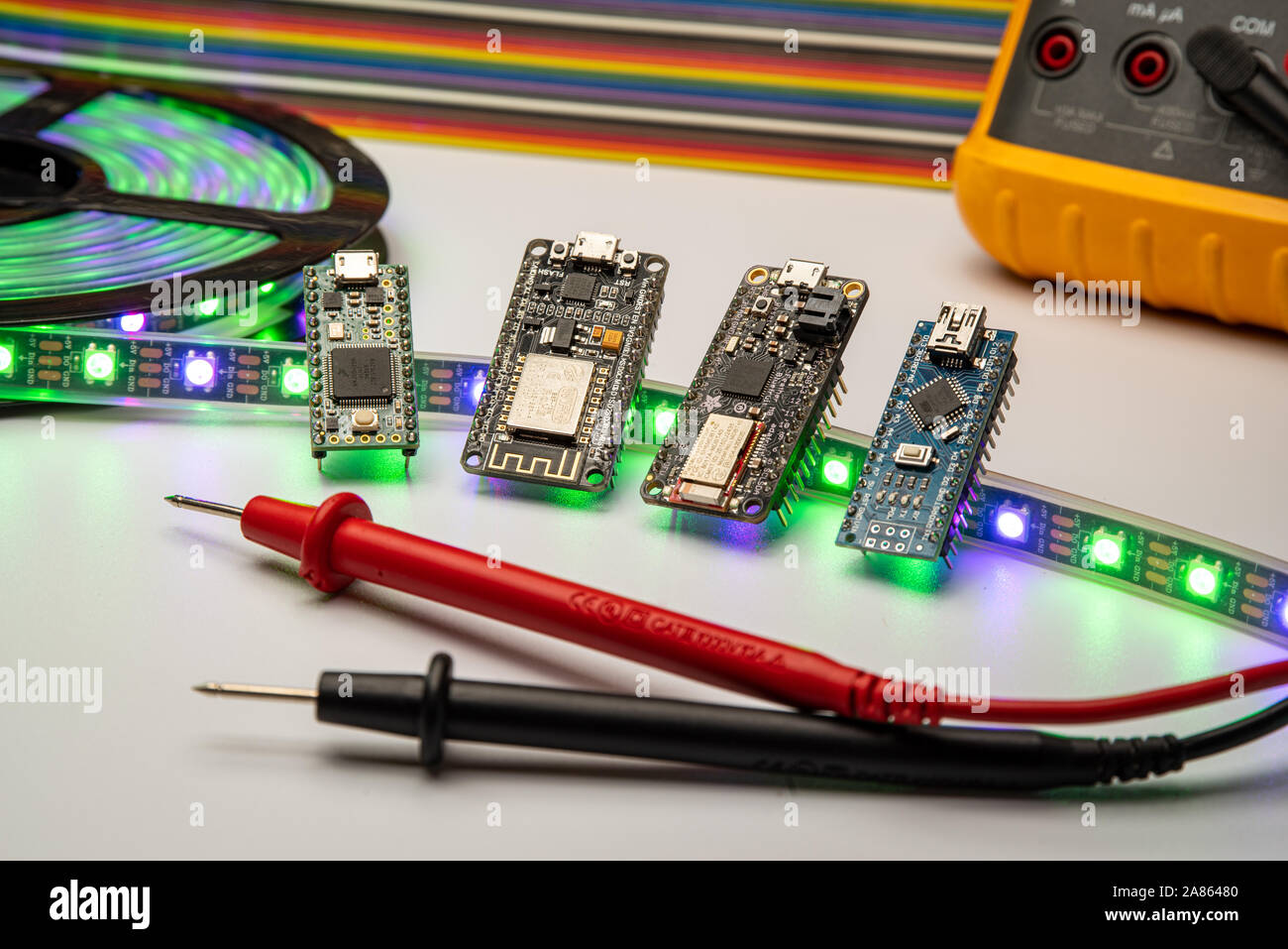 Selezione di piccole schede di sviluppo visualizzata con una striscia di LED, il metro e il ponticello dello sfondo. Schede madri includono minuscolo, piume, esp8266 e nano. Foto Stock