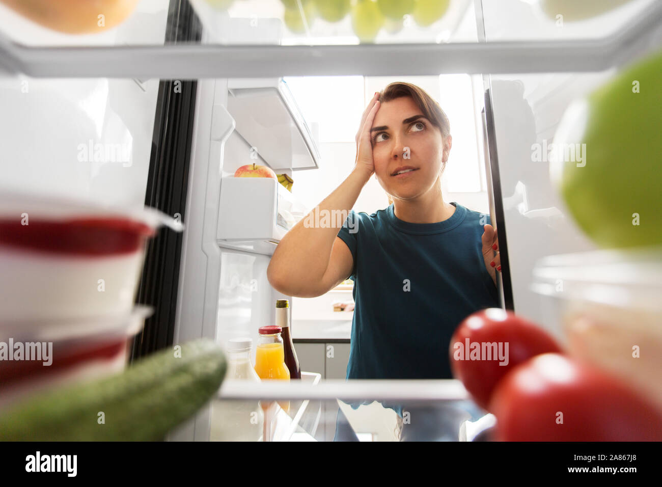 Crazy donna ad aprire il frigo tenendo la testa Foto Stock