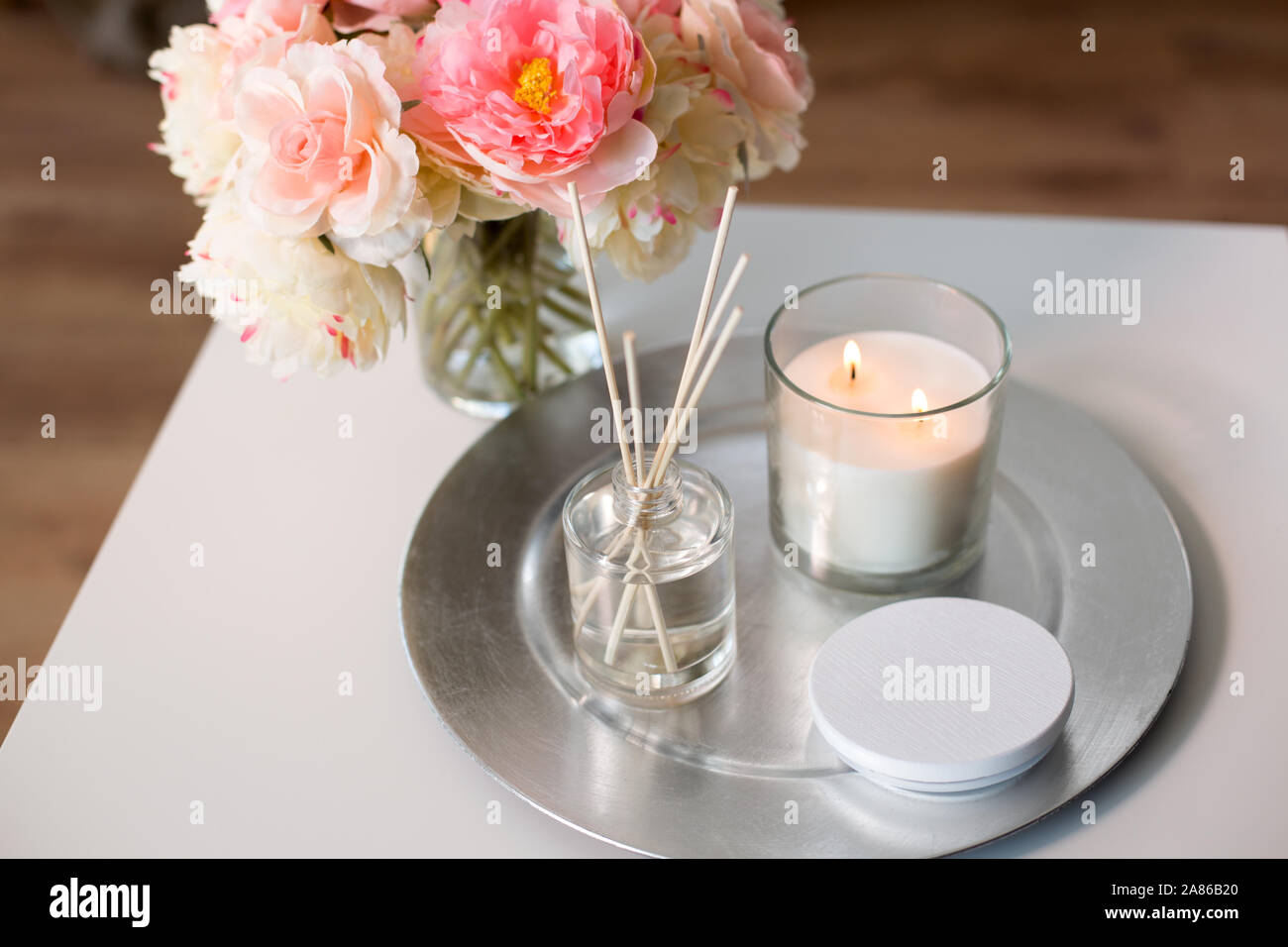 Aroma diffusore reed, candela e fiori sul tavolo Foto Stock