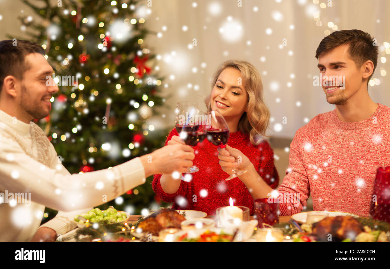 Felice gli amici a bere vino rosso alla festa di natale Foto Stock