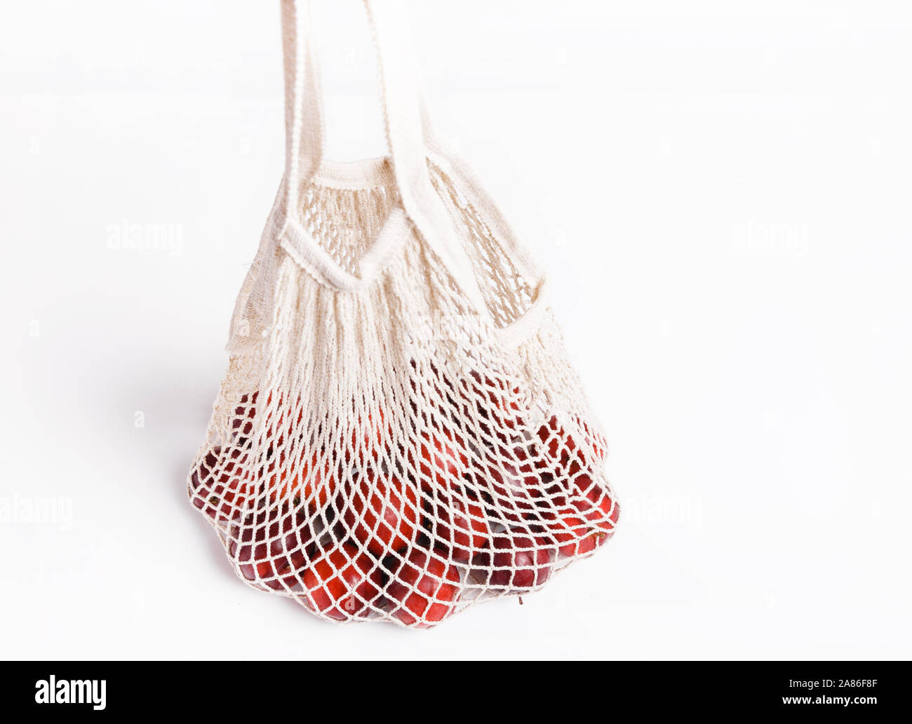 Mele biologiche in borsa di vimini per fare shopping su sfondo bianco, eco shopping bag il concetto. Foto Stock