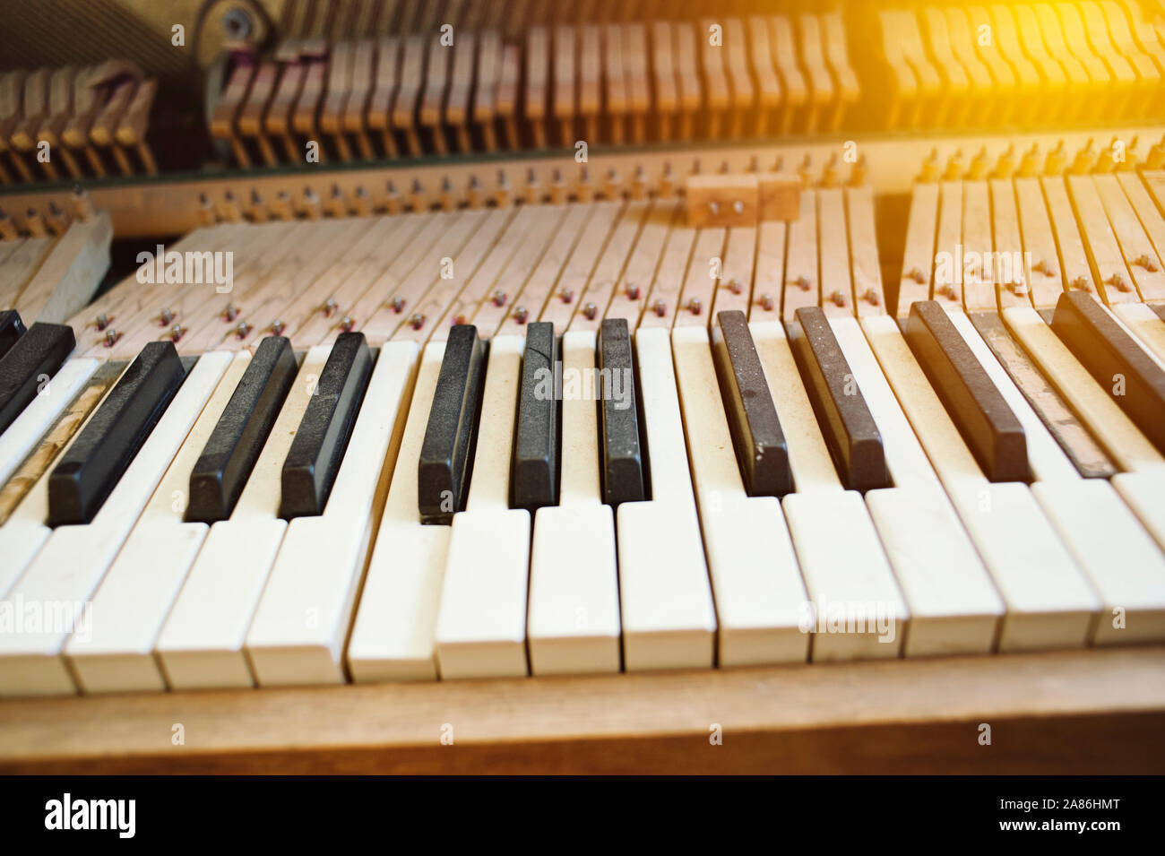 Polveroso vecchio pianoforte con tasti rotti e illuminazione calda Foto Stock