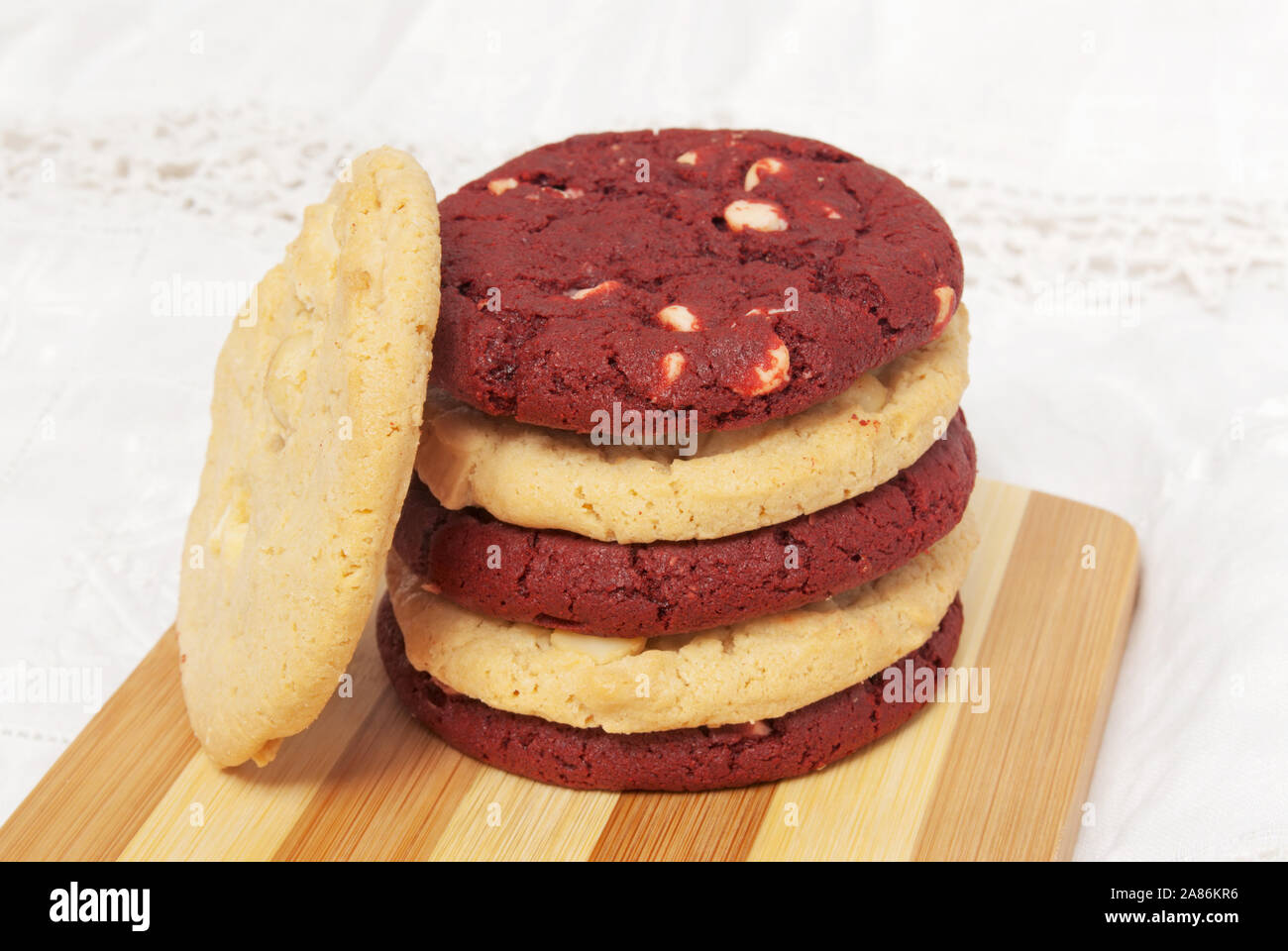 Pila di bianco dolci di cioccolato con nocciole di macadamia e velluto rosso i cookie su un tagliere formando colori alternati. Questi cookie sono un Natale e Foto Stock