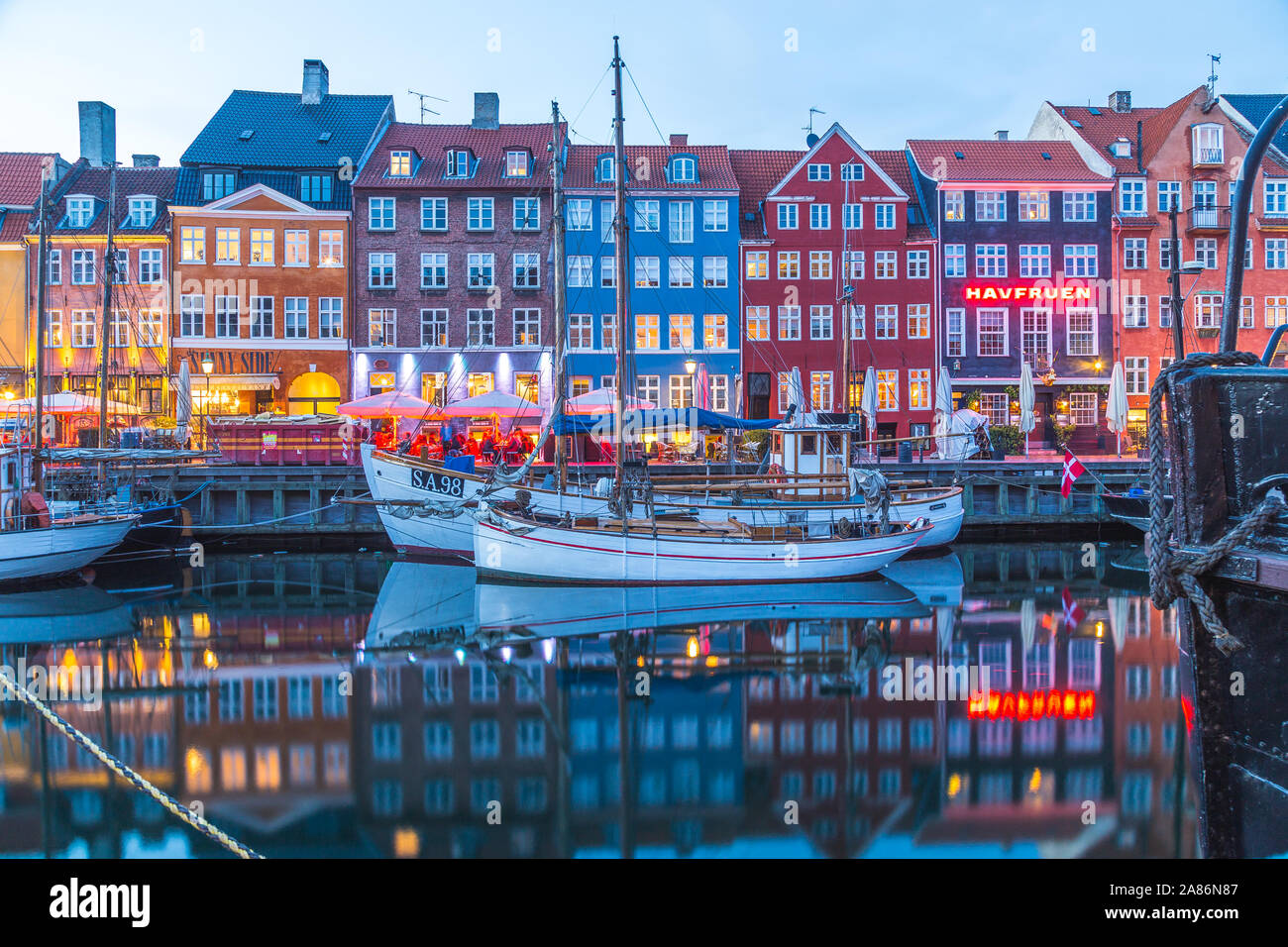COPENHAGEN, Danimarca - 22 Maggio 2017: Architettura e barche lungo Nyhavn in prima serata. Le riflessioni e le persone possono essere visti. Foto Stock