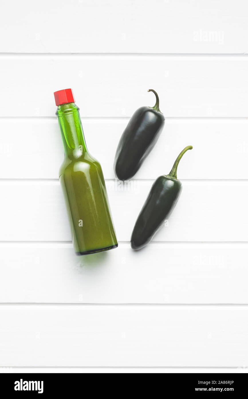 Verde peperoncini jalapeno e salsa Tabasco sul tavolo bianco. Vista dall'alto. Foto Stock