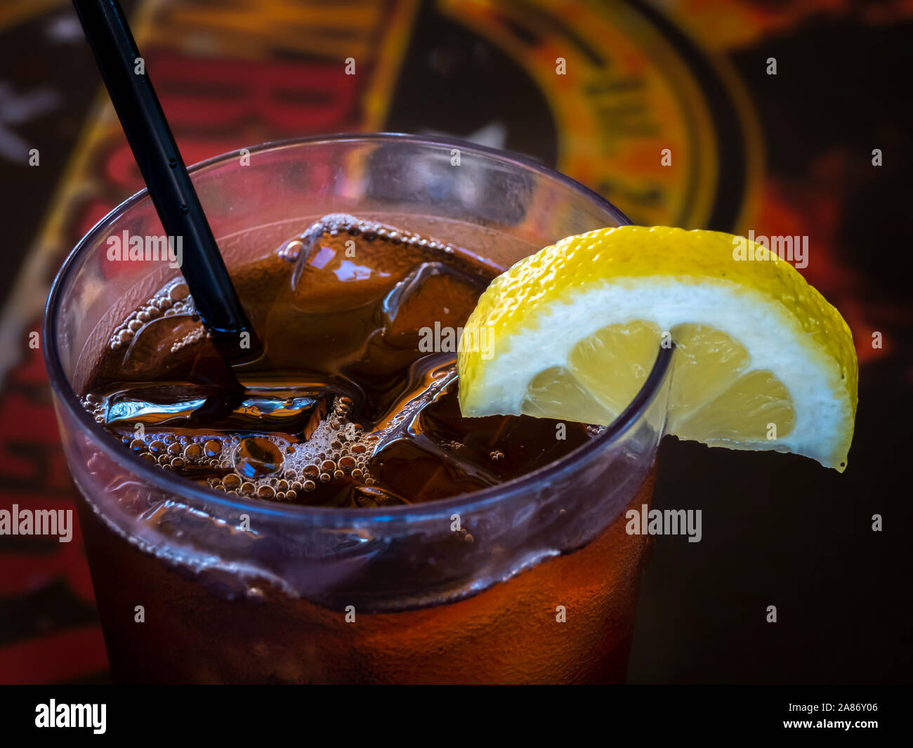 Cloaeup del bordo superiore del bicchiere riempito di tè freddo con una fettina di limone e paglia Foto Stock