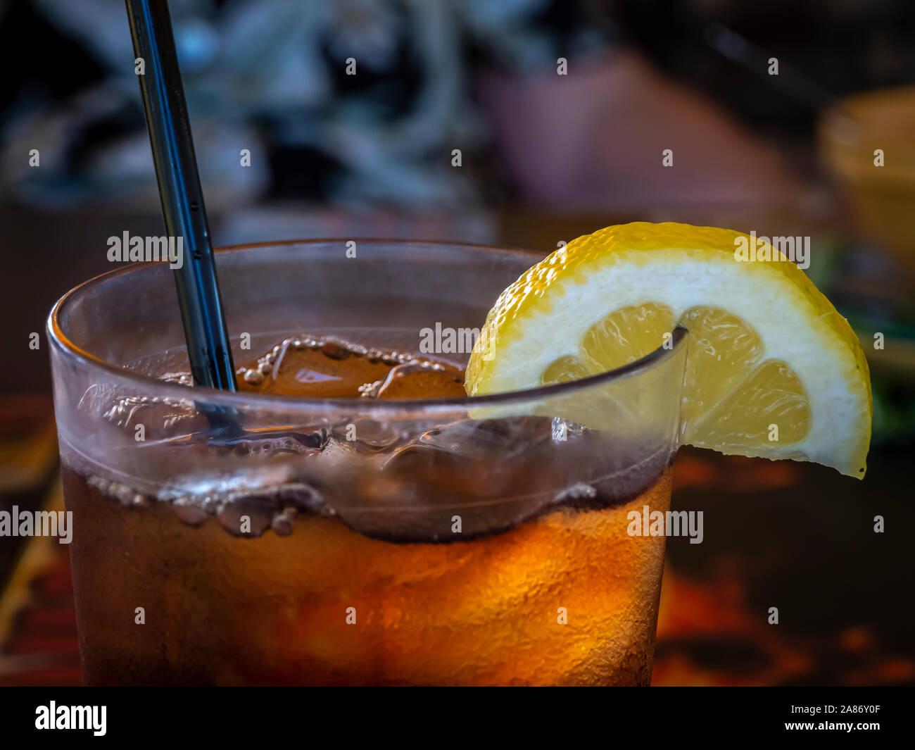 Cloaeup del bordo superiore del bicchiere riempito di tè freddo con una fettina di limone e paglia Foto Stock