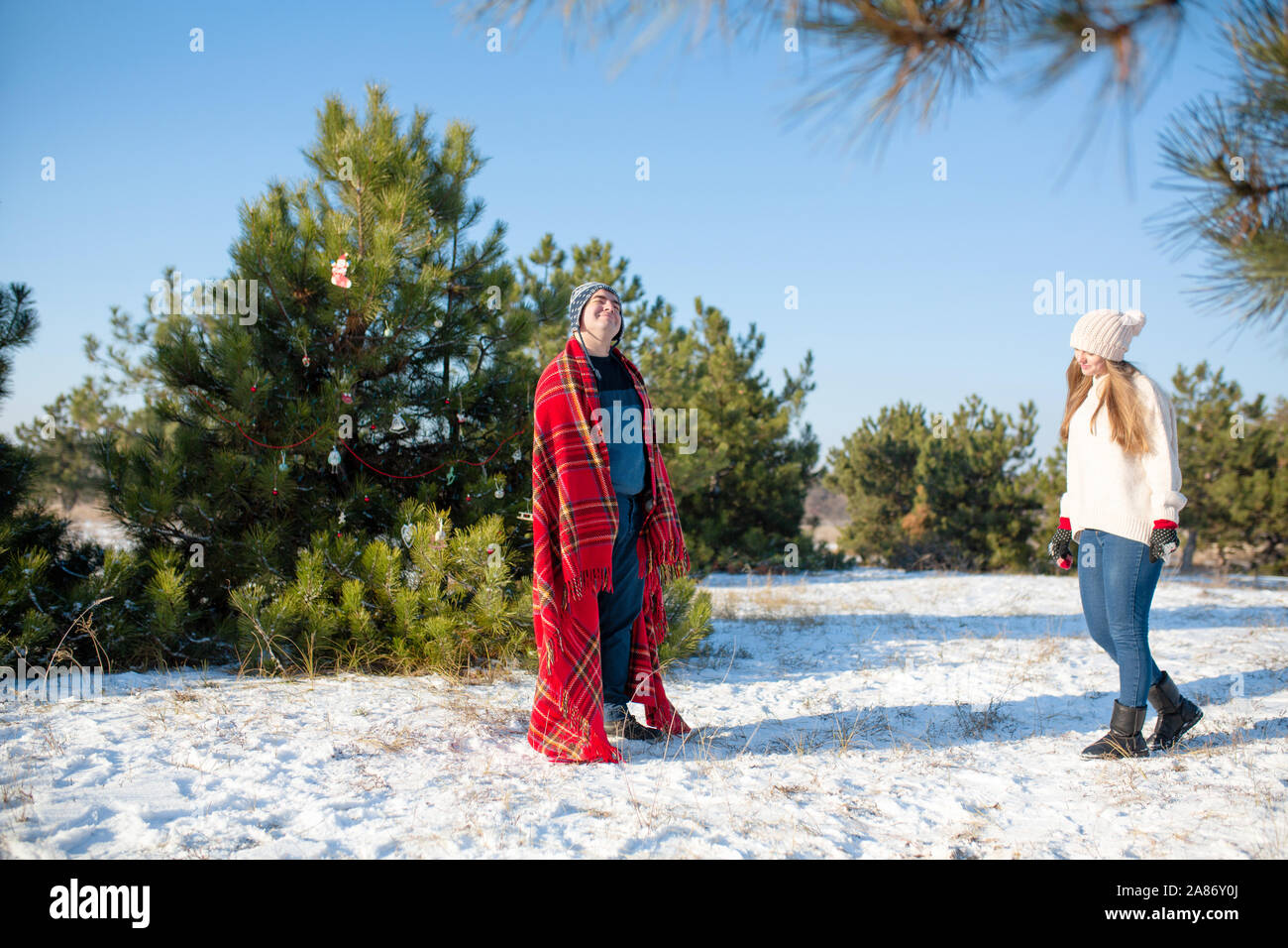 Passeggiata invernale nella foresta. Un ragazzo in un rosso plaid plaid pone come un supereroe, considerando che il plaid è il suo mantello. Il supereroe che meritano. Foto Stock