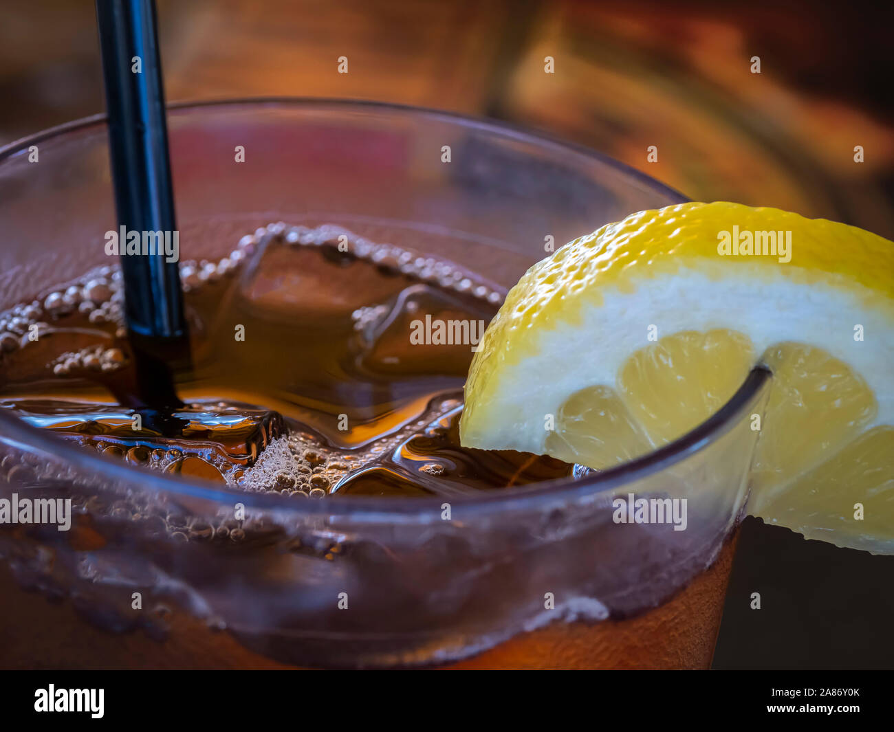 Cloaeup del bordo superiore del bicchiere riempito di tè freddo con una fettina di limone e paglia Foto Stock