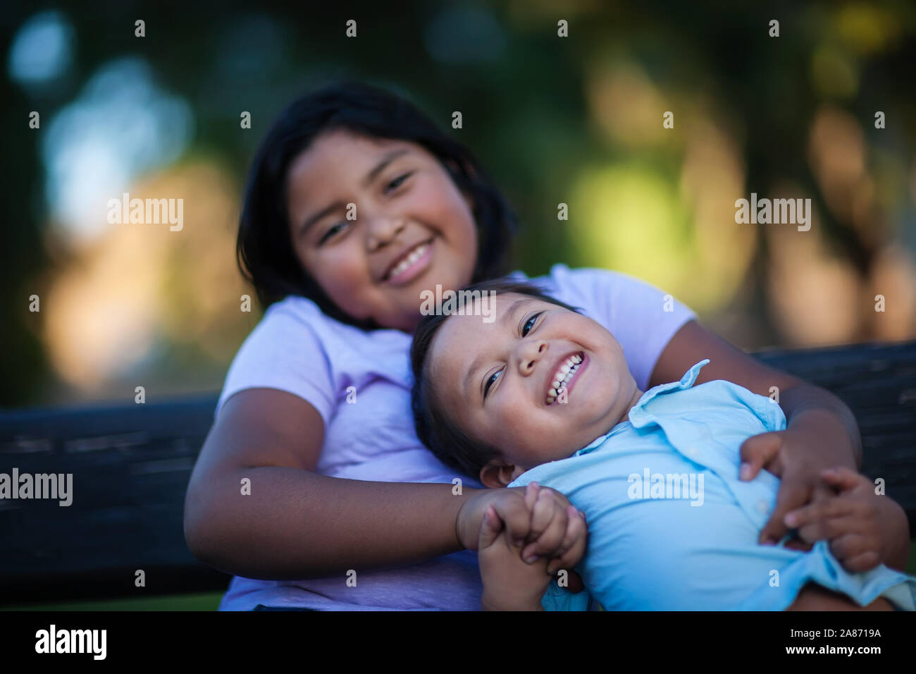 Piccolo fratello godendo la società di sua sorella come lui ride con un'espressione gioiosa e trattiene la sua mano. Foto Stock