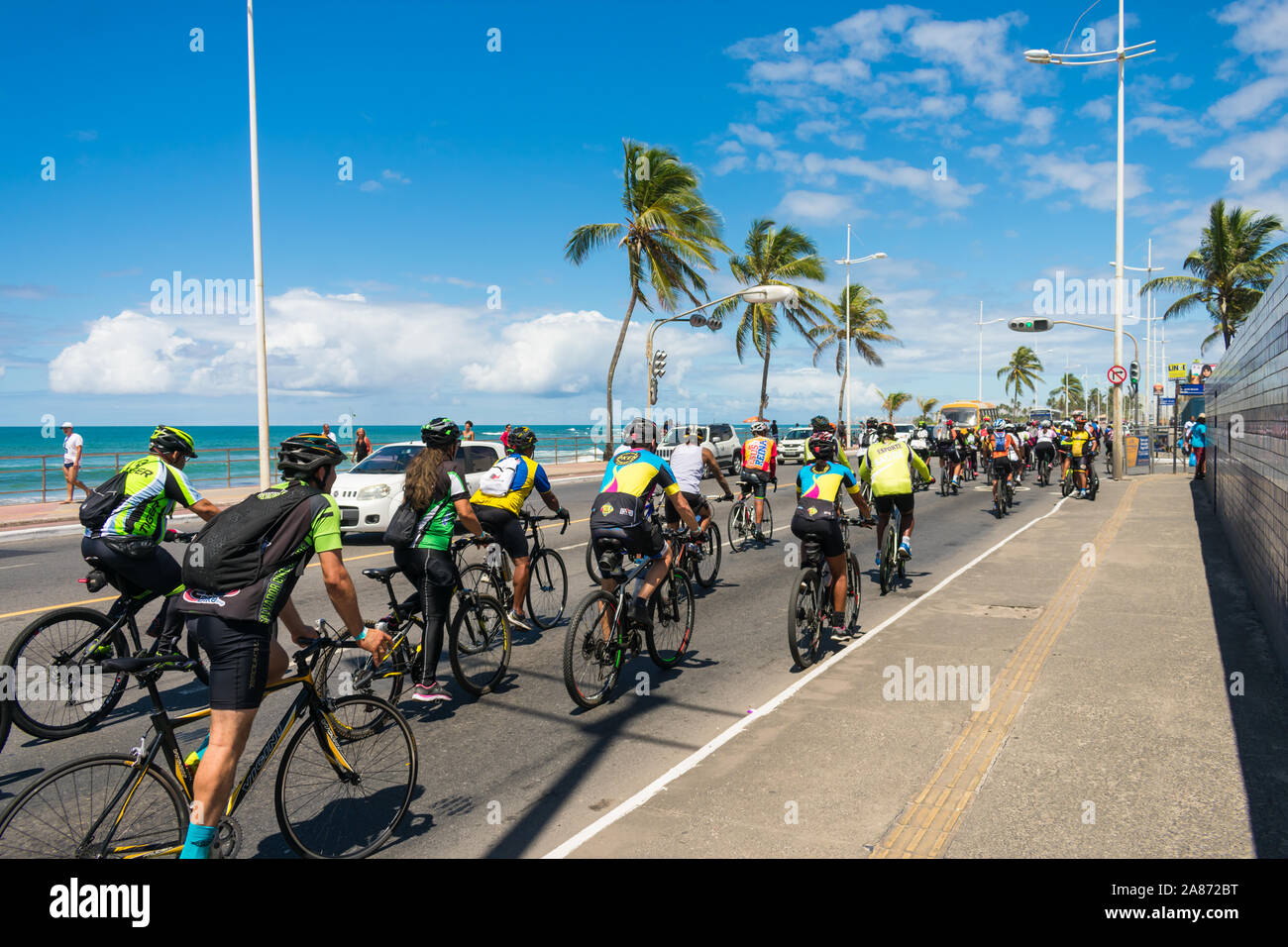 Un gruppo di ciclisti in sella per le strade del quartiere di Itapua sul mondo la Giornata senza automobili - spiaggia in background Foto Stock