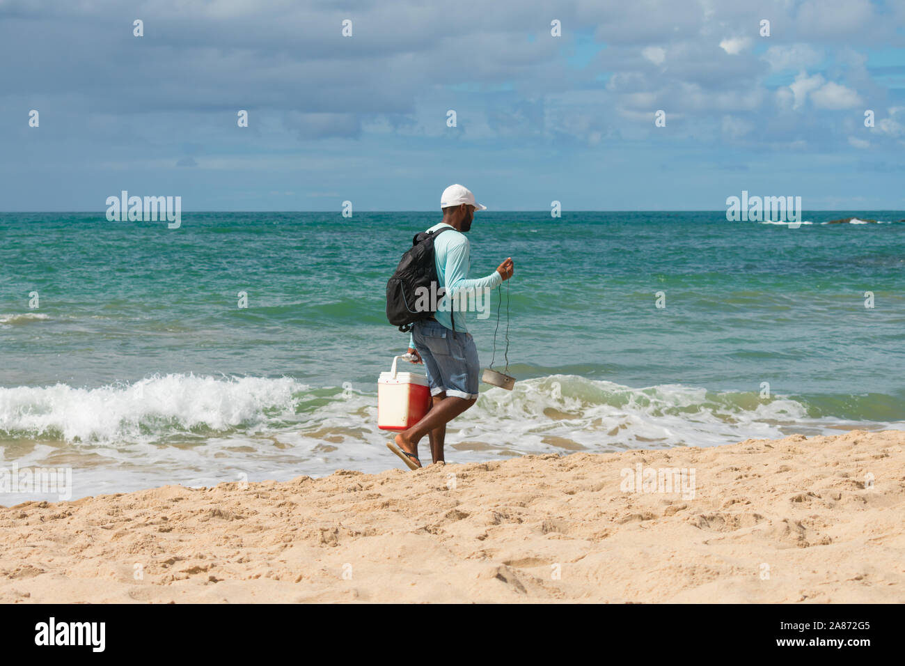 Salvador, Brasile - Circa nel settembre 2019: l'uomo con un braciere vendere queijo coalho (formaggio alla griglia) sulla spiaggia di Itapua - popolare beach snack in Salvador Foto Stock