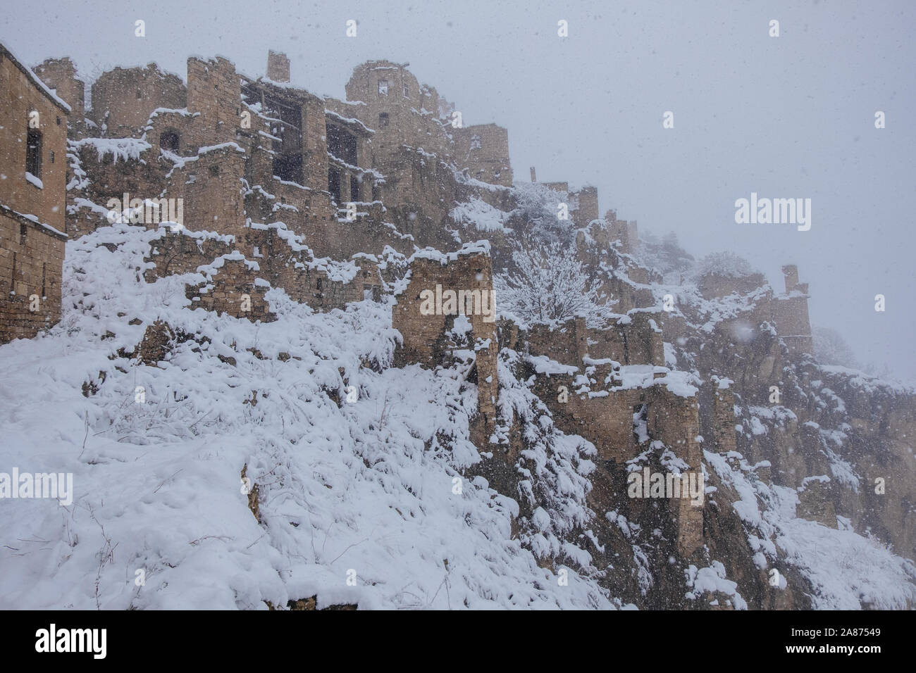 Antica città abbandonate Gamsutl nelle nebbiose invernali innevate montagne del Caucaso, in Daghestan, in Russia. Foto Stock