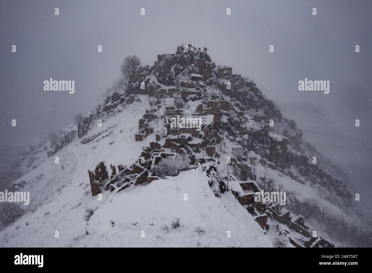 Vista aerea della città abbandonate Gamsutl nelle nebbiose invernali innevate montagne del Caucaso, in Daghestan, in Russia. Foto Stock