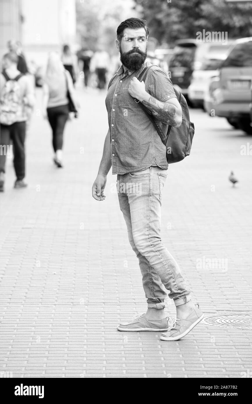 Hipster indossando uno zaino strada urbana dello sfondo. Uomo Barbuto viaggiare con lo zaino. Guy esplorare la città. Turismo confortevole. La vacanza estiva. Concetto di sightseeing. Zaino per il viaggio urbano. Foto Stock