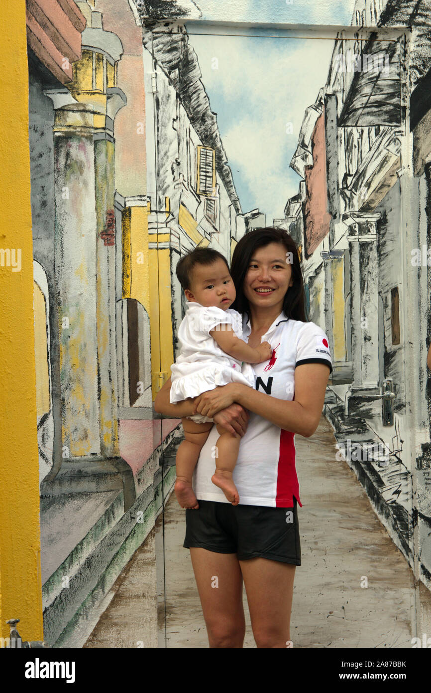 La madre e il bambino pone contro un murale su una parete di strada in Ipoh, Perak, Malaysia Foto Stock