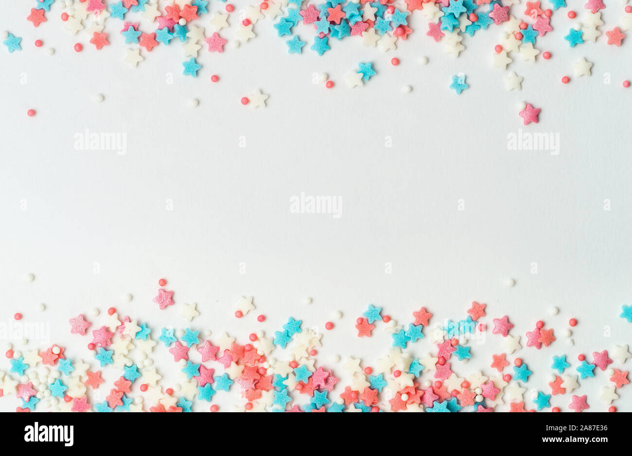 Festosa cornice di confine del pastello colorato spruzza su sfondo bianco con copia spazio nel centro. Cospargere di zucchero Punti e stelle, decorazione per torte e pasticceria. Vista superiore piatta o laici. Banner Foto Stock