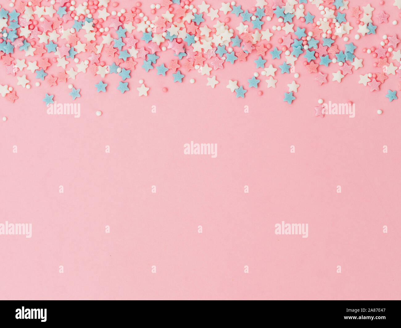 Festosa cornice di confine del pastello colorato spruzza su sfondo rosa, spazio copia top. Cospargere di zucchero Punti e stelle, decorazione per torte e pasticceria. Vista superiore o laici piatta Foto Stock