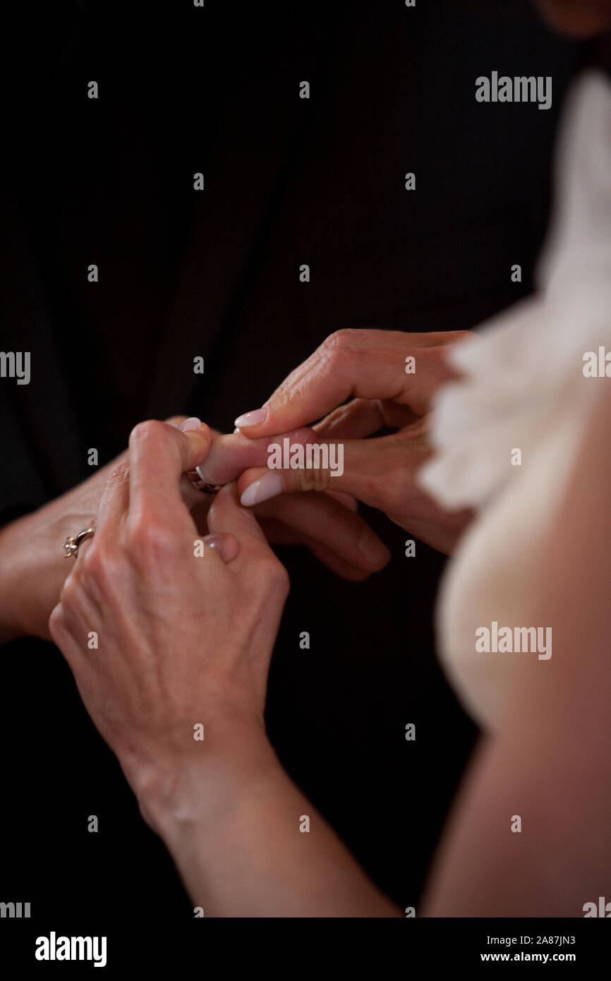 Un irriconoscibile sposa e lo sposo lo scambio degli anelli di nozze nella chiesa durante il cristiano la cerimonia nuziale Foto Stock
