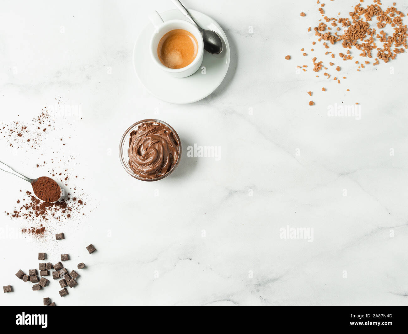 Piatto dolce sfondo laici. Cioccolato, zucchero, nocciola diffusione di cacao, cacao in polvere e la tazza di caffè su marmo bianco piano portapaziente con copia spazio. Si può utilizzare come mock up o offerte speciali per cafe o dolciumi Foto Stock