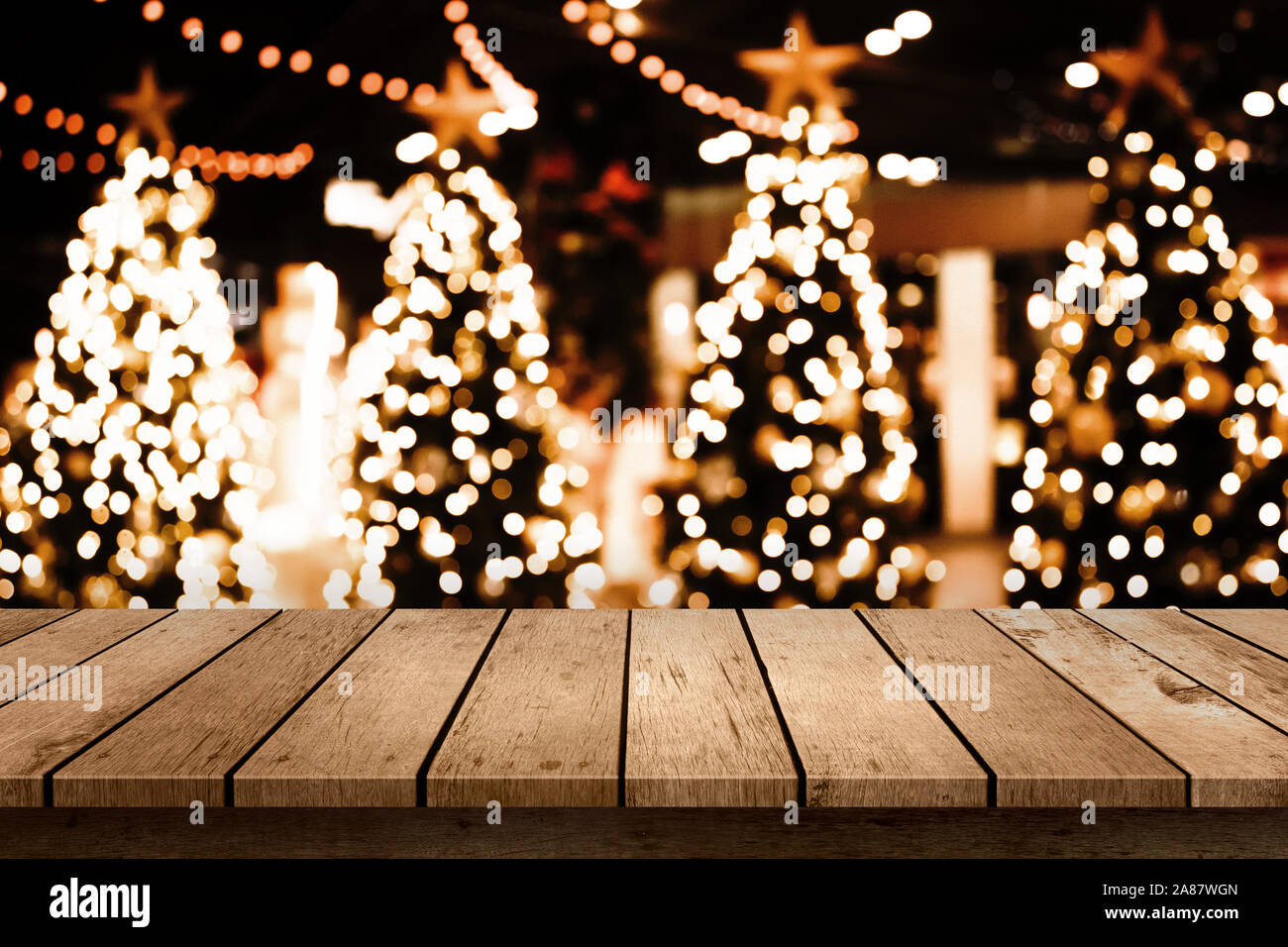 Tavola in legno top con albero di natale e la sfocatura della luce sfondo bokeh di fondo. Foto Stock