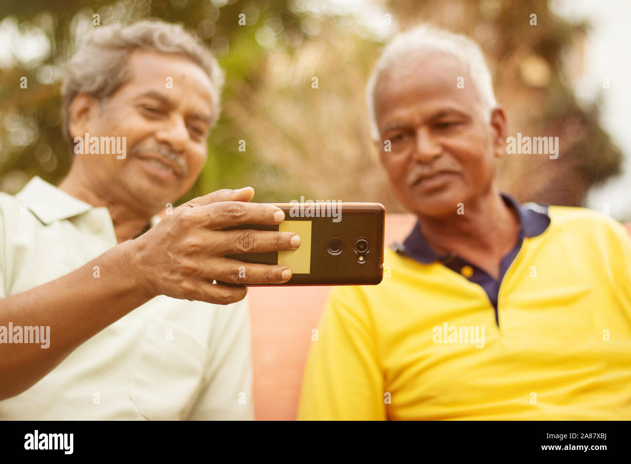 Messa a fuoco selettiva su telefono due felici uomini anziani occupato nella visione outdoor mobile - Concetto di senior persone utilizzando la tecnologia - Due Coppia di vecchi amici Foto Stock