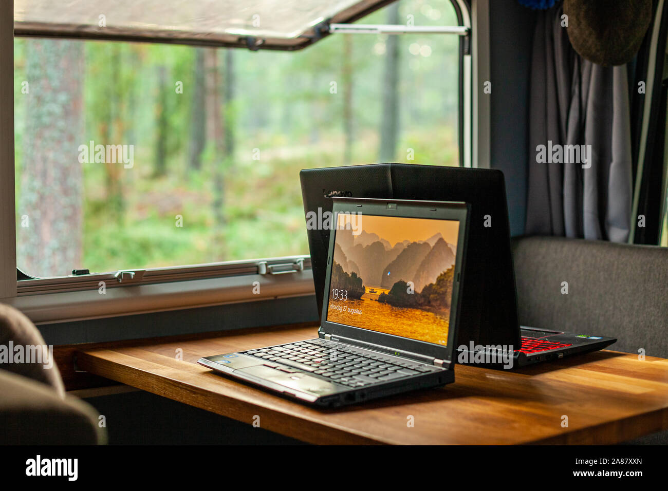 Spazio di lavoro con computer portatili in un camper nel bosco Foto Stock