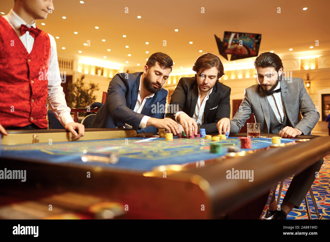 Gruppo uomo giocatore in un vestito al tavolo della roulette giocando a poker in un casinò. Foto Stock