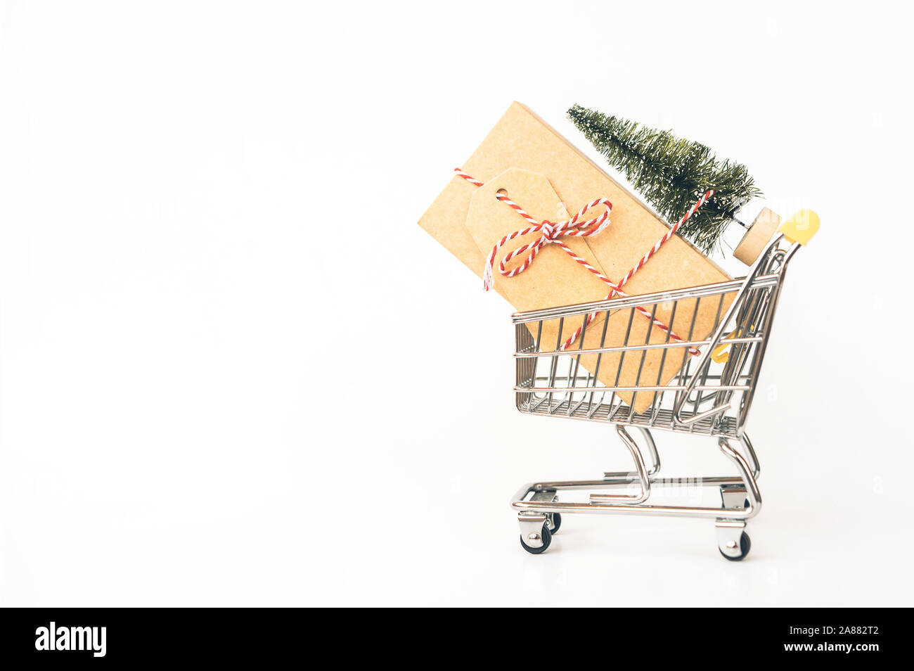 Carrello metallico per lo shopping con un grande regalo, albero di Natale artificiale. Foto Stock