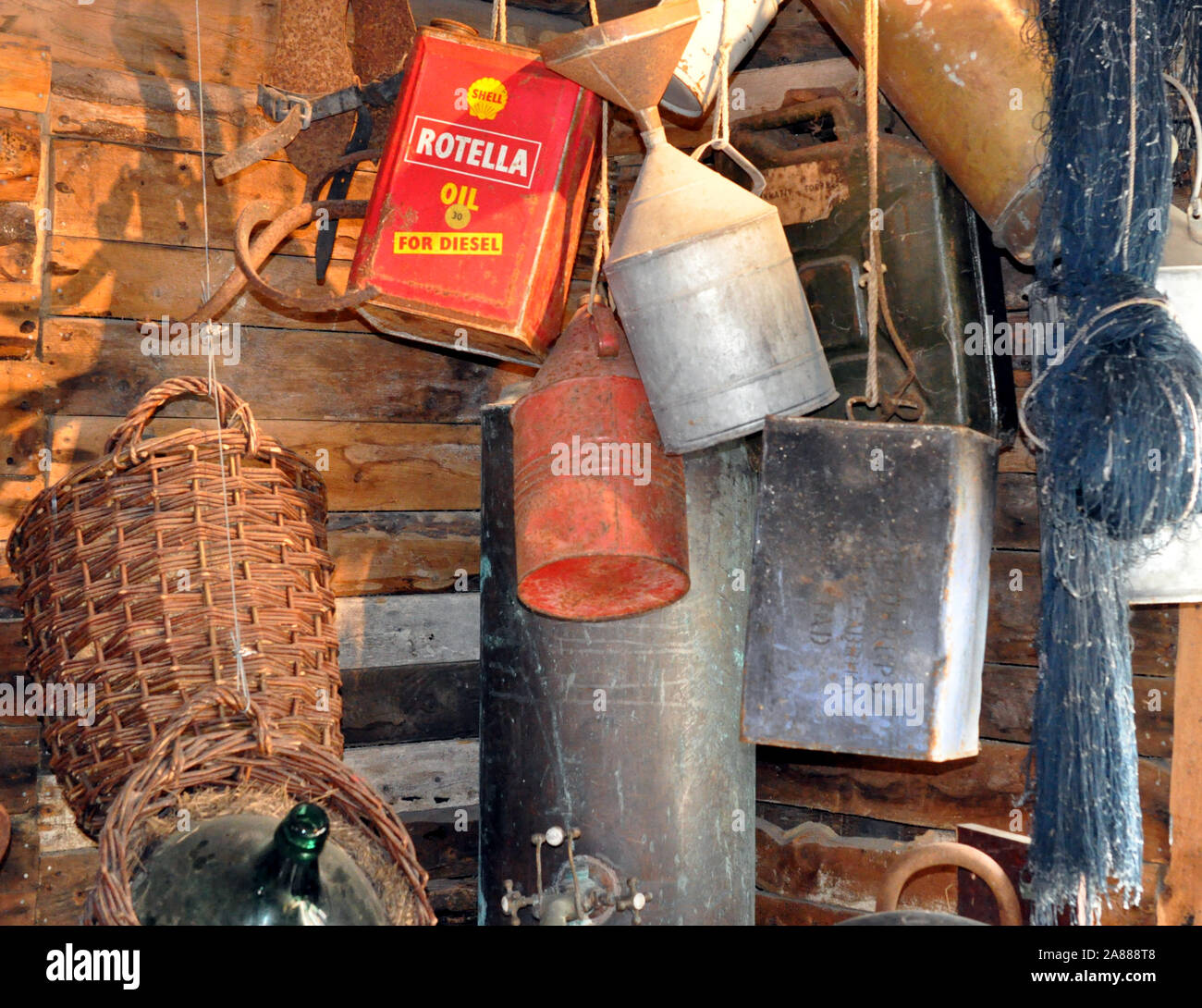 Una raccolta di vecchie lattine di olio, compresi Rotella Oil da parte di Shell, appeso in un capannone di legno. Foto Stock