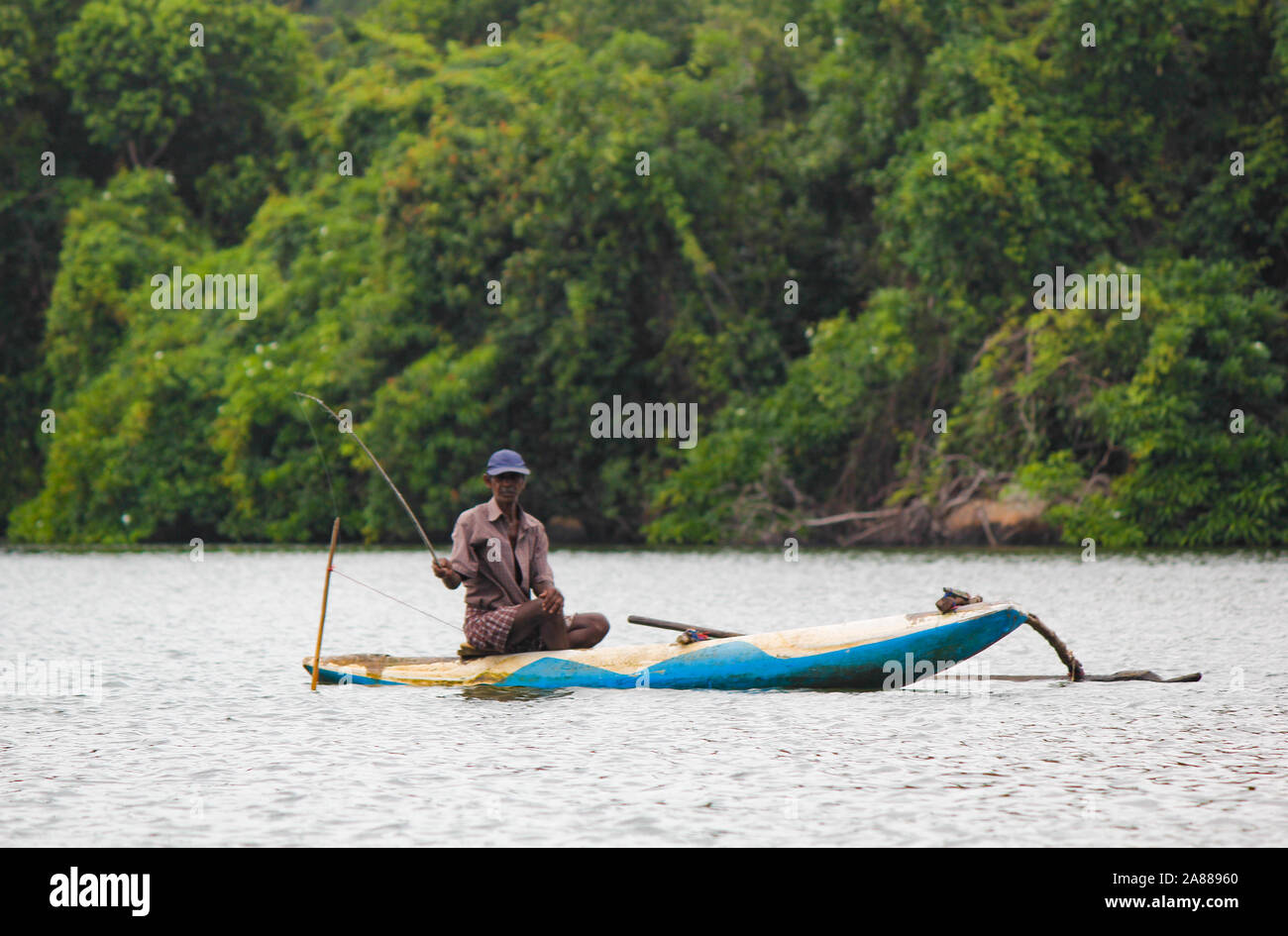 Sri Lanka fiume, turismo di Srilankan, pescatore del lago in azione quando la pesca al crepuscolo, la cultura di Srilankan, e tourism.wooden barca con una canna da pesca. Foto Stock