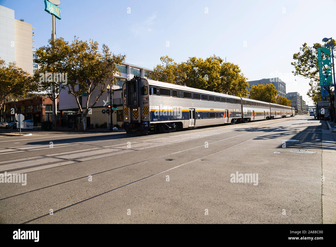 Enorme treno Amtrak guidando attraverso il Jack London Square, lungo Embarcadero di Oakland, California, Stati Uniti d'America Foto Stock