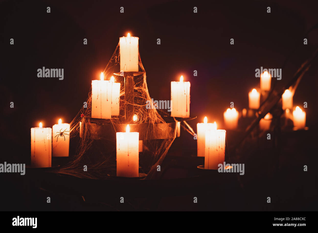 Candele bruciano in vecchio lampadario in un seminterrato buio. Scena di Halloween o concetto: spooky vecchio candelabro avvolto con ragnatele Foto Stock
