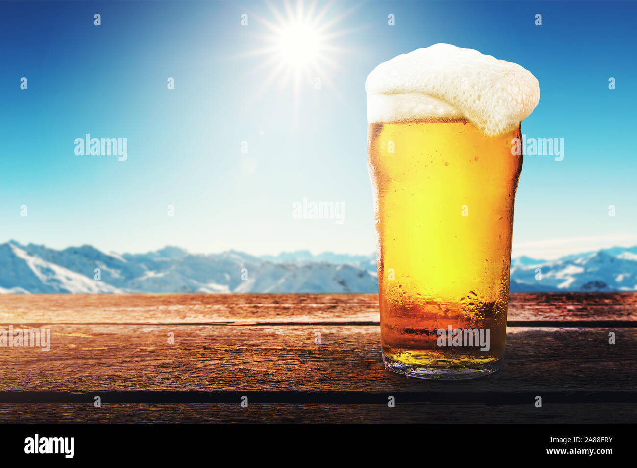 Apres Ski - birra fredda vetro su tavola con inverno pieno di sole montagne paesaggio allo ski resort. spazio copia Foto Stock