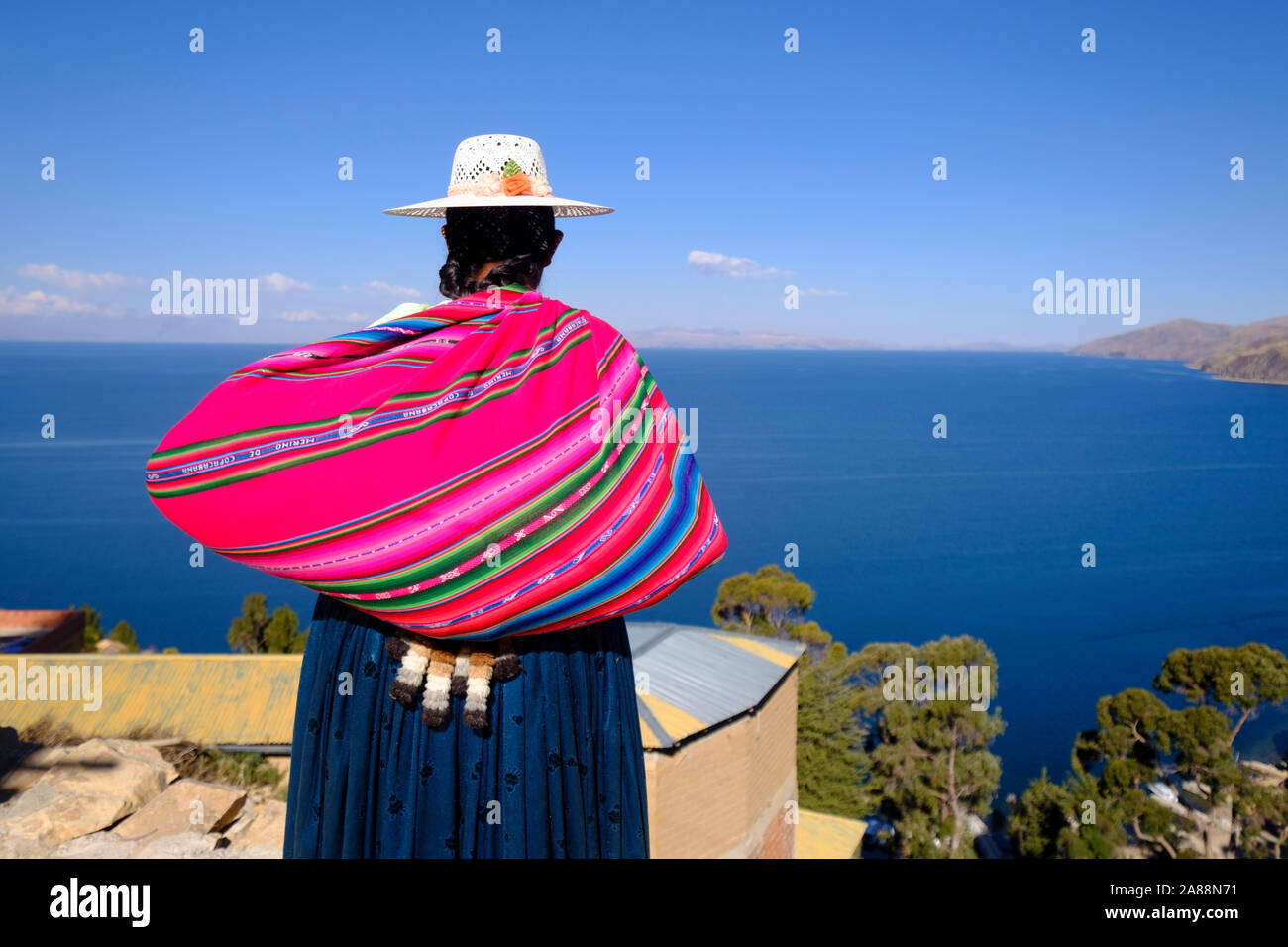 Locali di donna che indossa un cappello di fantasia e portante un colorato tradizionale sacchetto realizzato con lana merinos sull'isola del sole nel Lago Titicaca, Bolivia Foto Stock