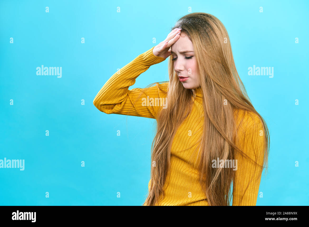 Ritratto di una bella donna in pullover turtleneck su blu stress di fondo e mal di testa con dolore da emicrania Foto Stock