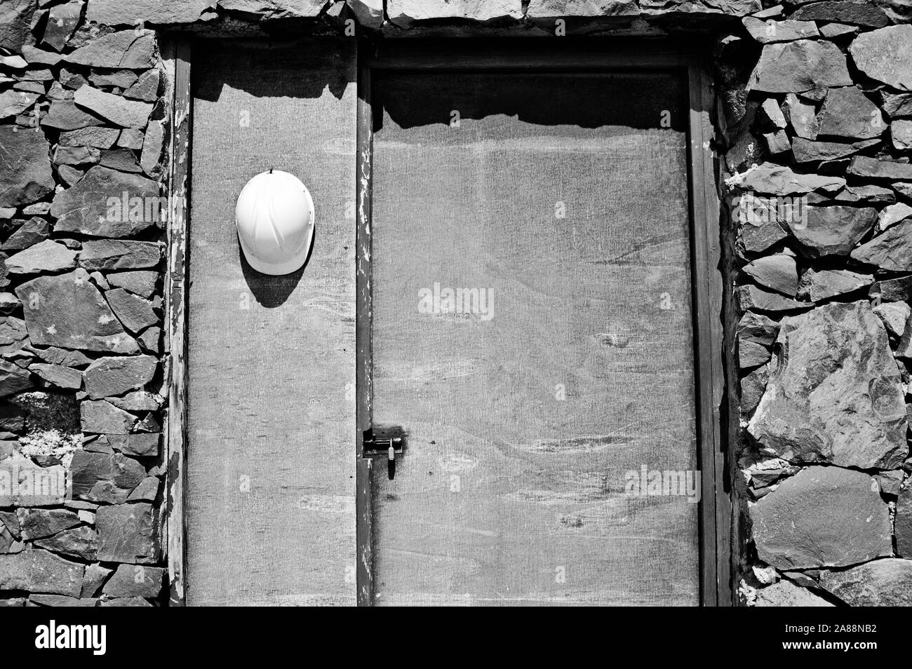 Lavoratore bianco casco appeso su una vecchia porta di legno di una casa in pietra (Achadas Da Cruz, Madeira, Portogallo, Europa) Foto Stock