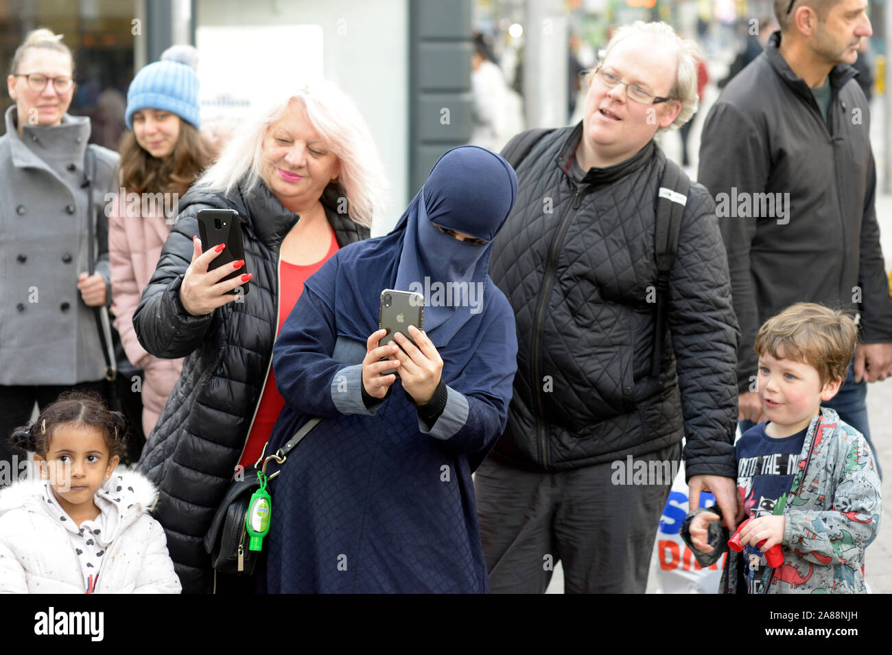 Varie persone che guardano un burattinaio. Un musulmano in niqab. Foto Stock