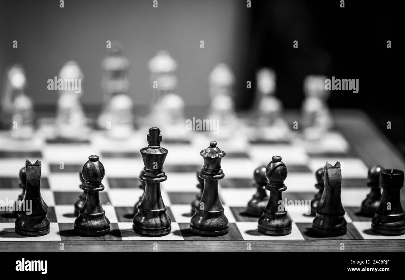 Monocromatico profondità di campo (messa a fuoco selettiva) immagine con scacchi in legno pezzi su un tavolo di legno prima di un concorso professionale. Foto Stock