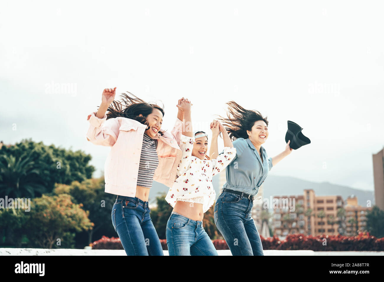 Felice Asian Girls jumping insieme all'aperto - Giovani donne amici divertendosi durante la pausa universitaria ballare e festeggiare al di fuori Foto Stock