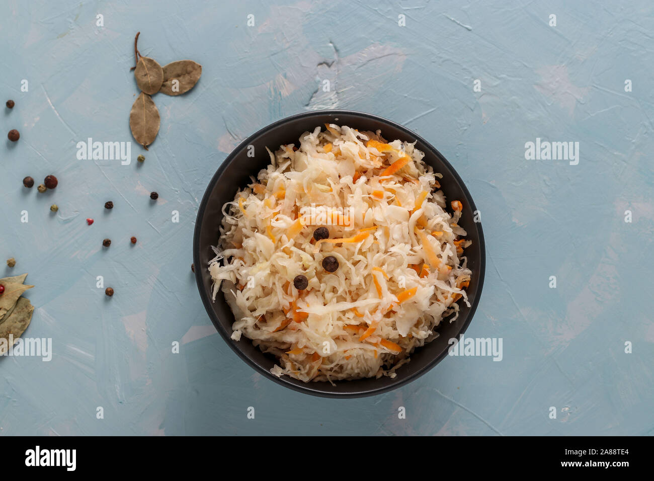 Crauti fatti in casa con le carote in una ciotola su un fondo azzurro, alimento fermentato Foto Stock