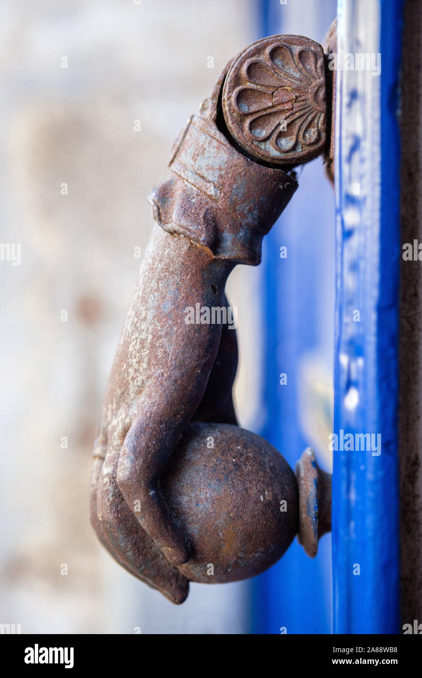 La porta di metallo respingente che rappresenta una mano che tiene una ciotola su una blu porta in legno Foto Stock