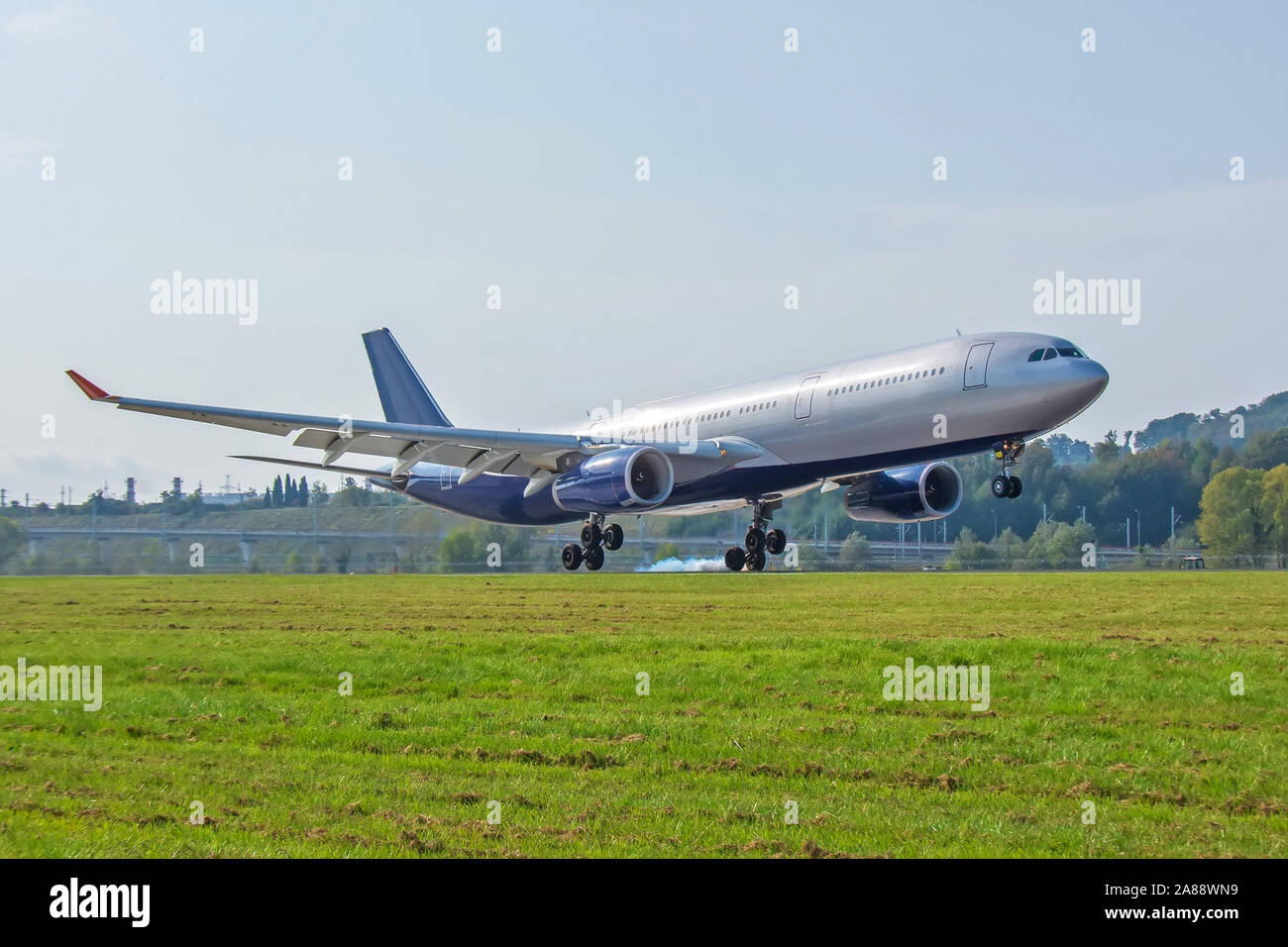 Grandi aerei passeggeri di atterraggio sulla pista vista laterale touch down con fumo di pneumatici Foto Stock